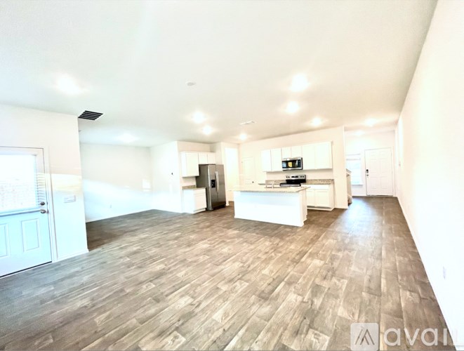 A spacious living room with wooden flooring and white walls.