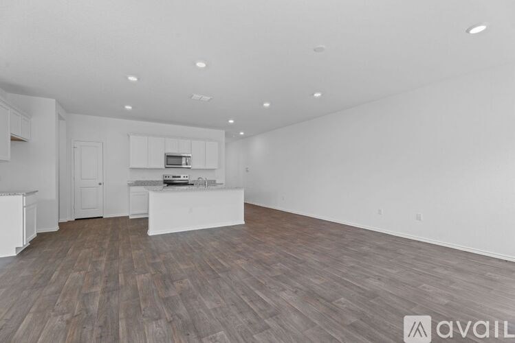 A spacious room with wooden flooring and white walls.