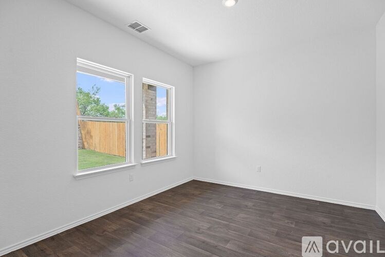 A room with two windows and a wooden floor.