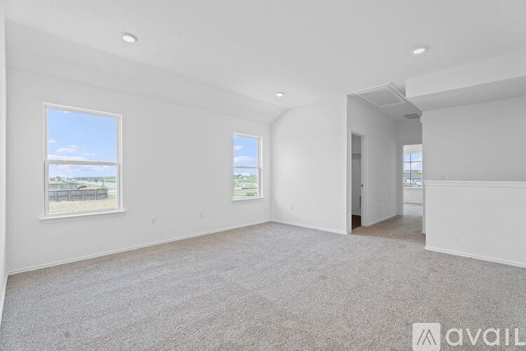 A spacious, empty room with a carpeted floor and two windows.