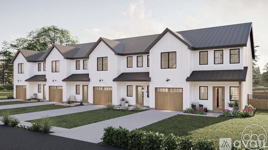 A modern house with a black roof and white walls is surrounded by a well-manicured lawn.