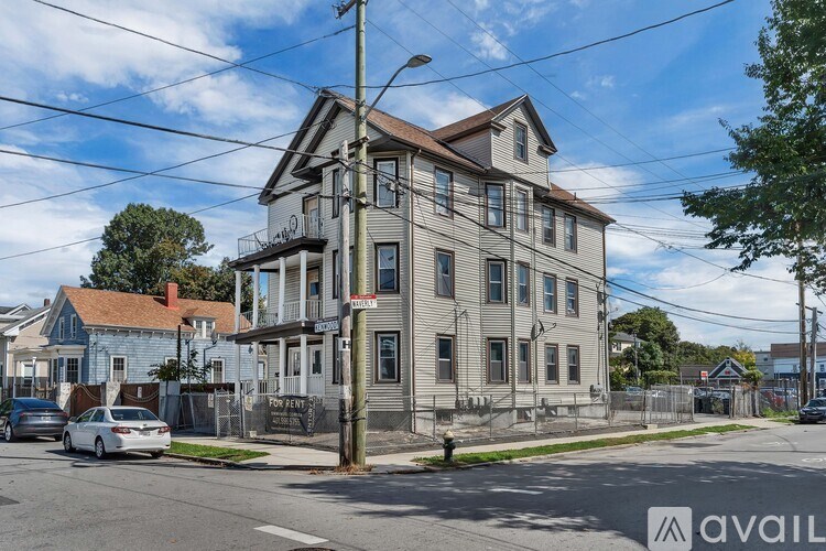 A large, two-story building with a balcony on the second floor is situated on a street corner.