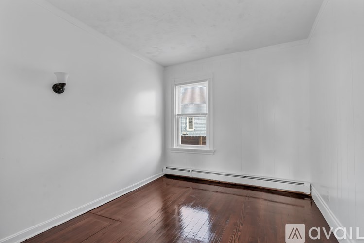 A room with a window and wooden flooring.