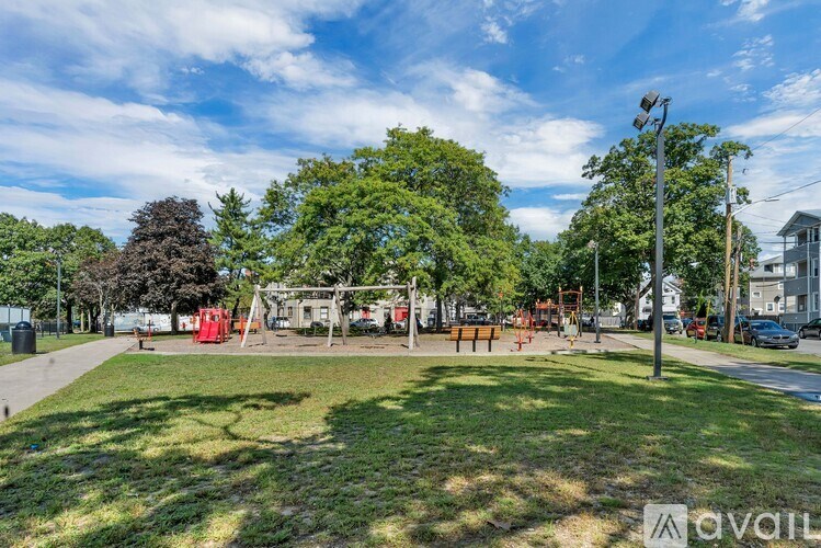A park with a playground and trees under a blue sky.