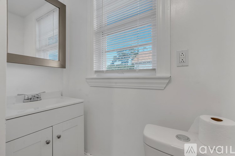 A white bathroom with a toilet, sink, and mirror.