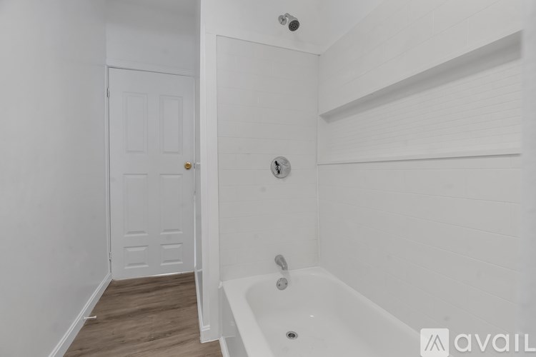 A white bathroom with a tub and a door.