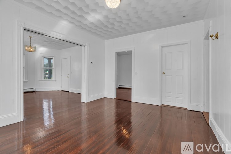 A room with white walls and wooden floors is available for rent.