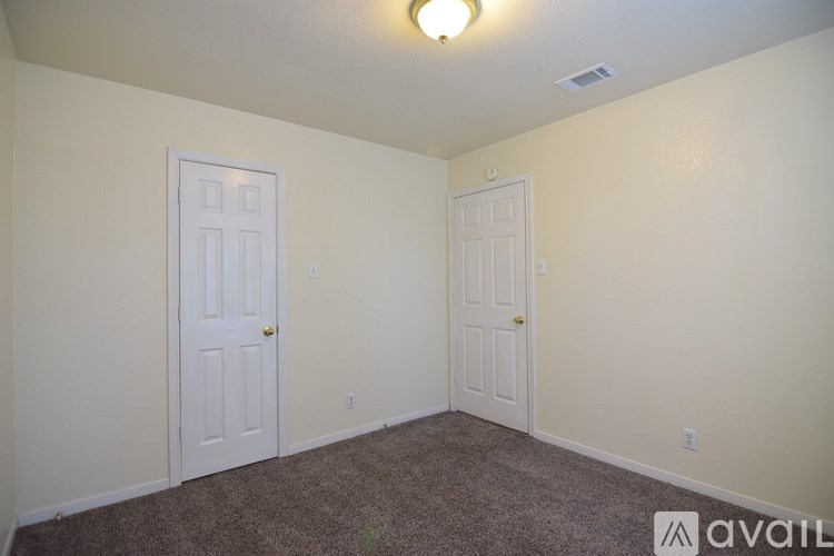 A room with two doors and carpeted floor.