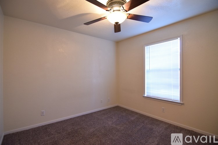 A room with a ceiling fan and a window with blinds.