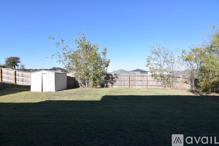 A grassy field with a fence and a shed in the background.