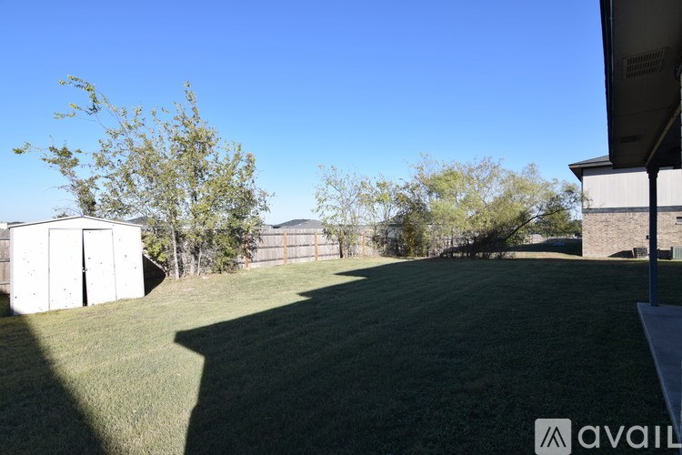 A grassy field with a building and trees in the distance.