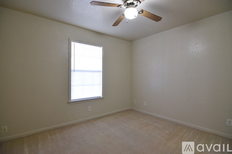 A room with a ceiling fan and a window letting in light.