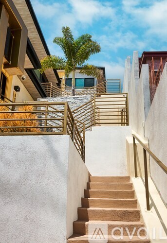 A staircase with a metal railing leads up to a balcony with a tree.