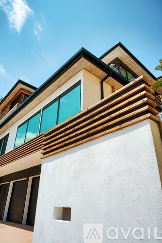 A modern house with a white wall and a brown roof.