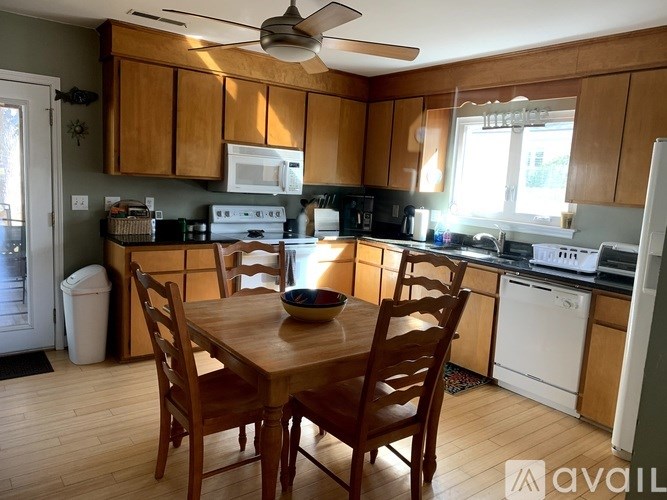 A kitchen with wooden cabinets and a table with chairs.