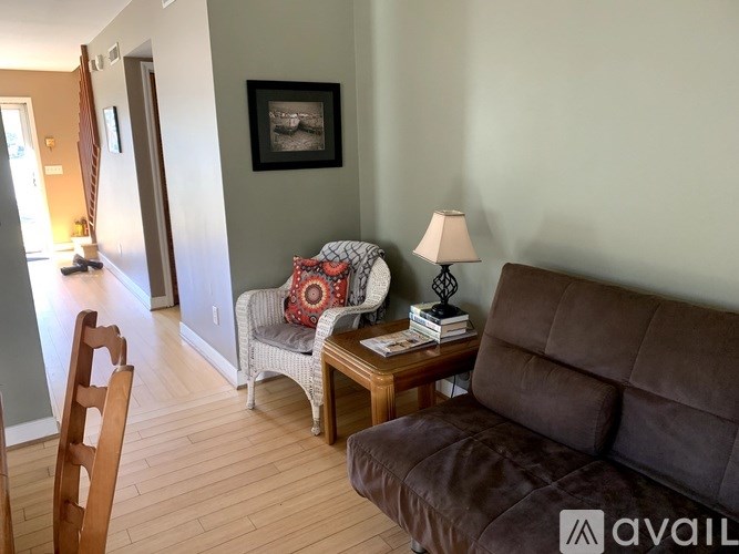 A living room with a brown couch, a chair, a small table with a lamp and a picture frame on the wall.