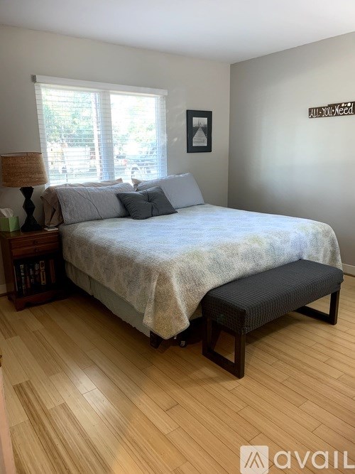 A bedroom with a bed, a bench, and a window.