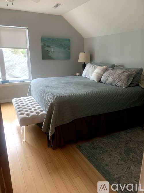 A bedroom with a bed, pillows, and a window.