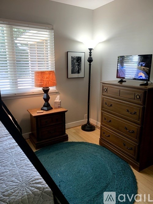 A bedroom with a bed, a dresser, a lamp and a television.