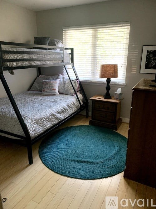 A bedroom with a bunk bed and a small table with a lamp.