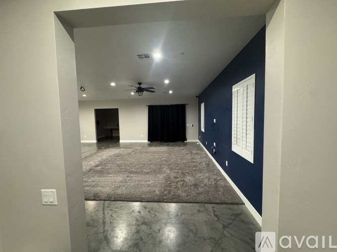 A spacious room with a ceiling fan and a rug on the floor.