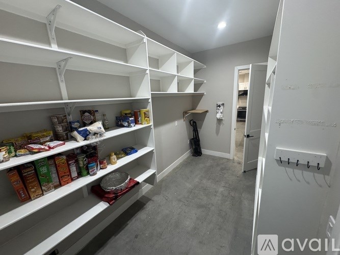 A pantry with white shelves and food items on the shelves.