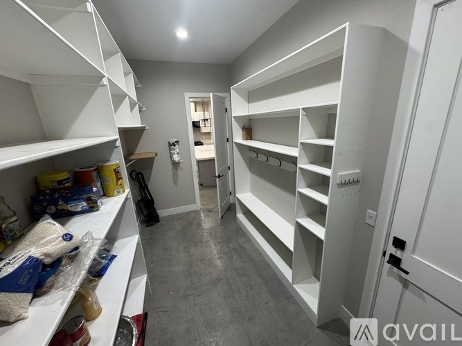A storage room with white shelving units and a door on the right.