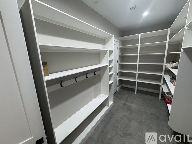 A large, empty walk-in closet with white shelving and a grey floor.