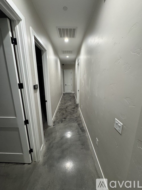 A long hallway with a door on the left and a light switch on the wall.