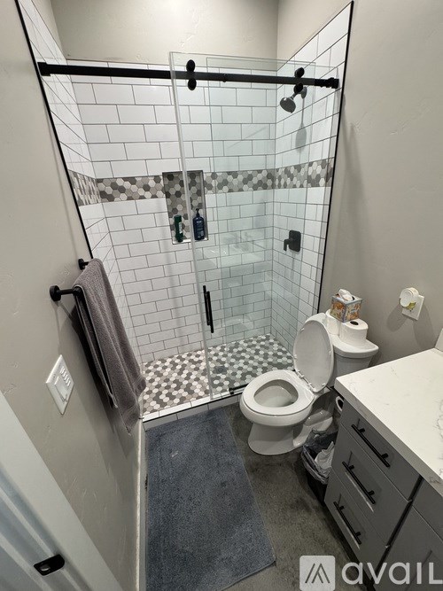 A bathroom with a toilet, a shower with a glass door, and a towel hanging on the wall.