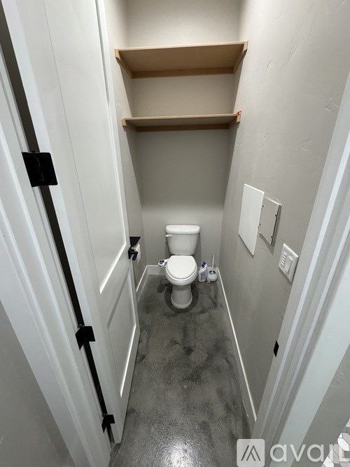 A small bathroom with a toilet and a shelf.