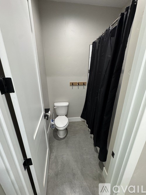 A bathroom with a toilet and a black robe hanging on the wall.