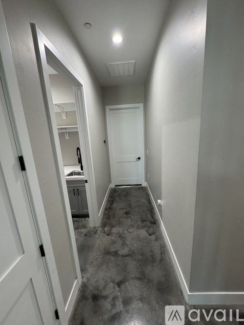 A hallway with a carpeted floor and a door at the end.