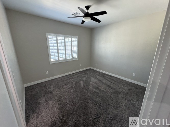 A room with a ceiling fan and a window with blinds.