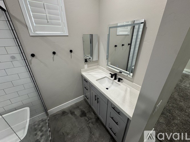 A bathroom with a sink, mirror, and shower.