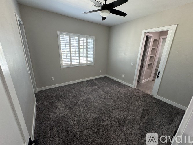 A room with a ceiling fan and carpeted floor.