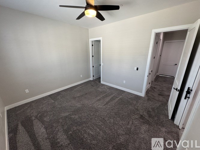 A room with a ceiling fan and carpeted floor.