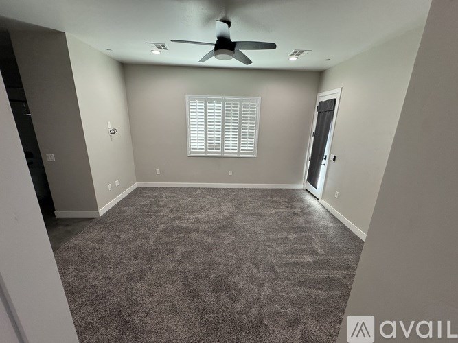 A room with a carpeted floor and a ceiling fan.