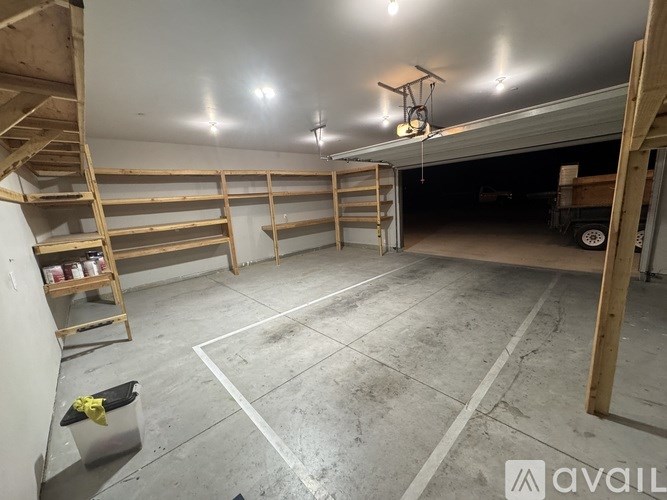 A large, empty garage with a ladder and shelves.