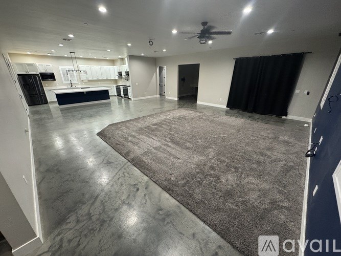 A spacious room with a grey carpet and a ceiling fan.