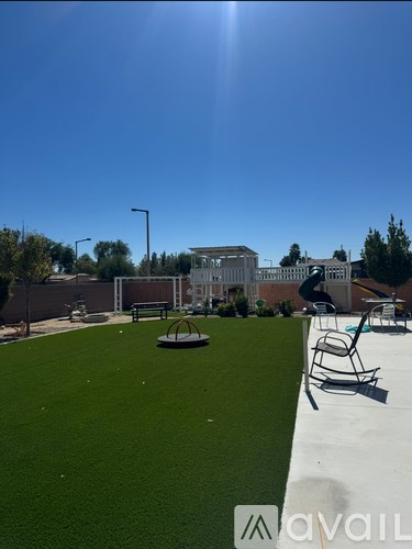 A sunny day at the park with a playground and a building in the background.