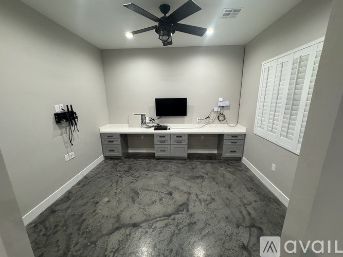 A room with a ceiling fan and a desk with a computer.