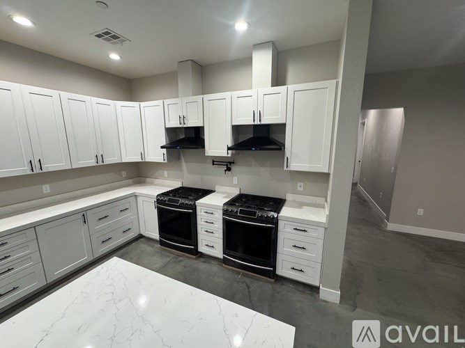 A kitchen with white cabinets and a marble countertop.