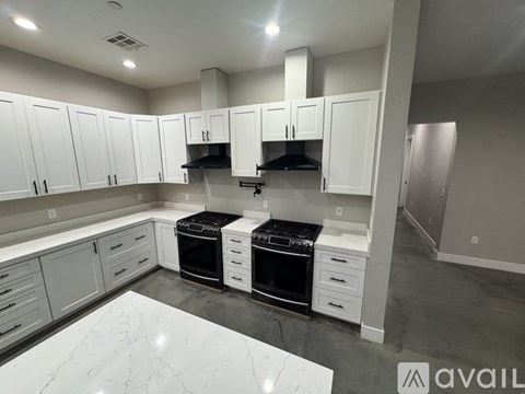 A kitchen with white cabinets and a marble countertop.