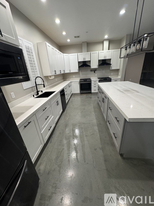 A modern kitchen with white cabinets and black appliances.