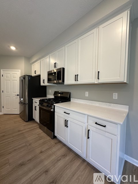 A kitchen with white cabinets and a black refrigerator.