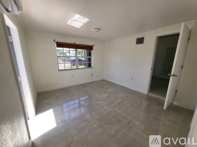 A room with a tiled floor and a window with blinds.