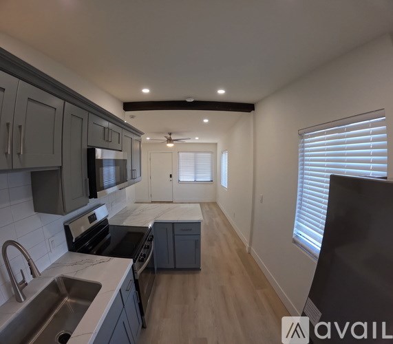 A kitchen with a sink, stove, and cabinets.