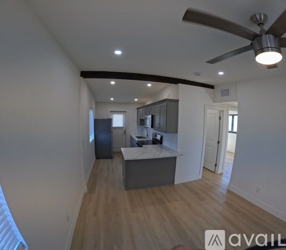 A modern kitchen with a large island and a ceiling fan.
