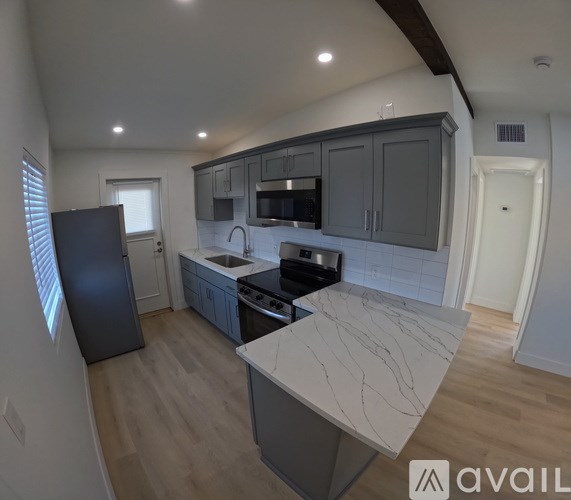 A kitchen with a marble countertop and wooden floors.